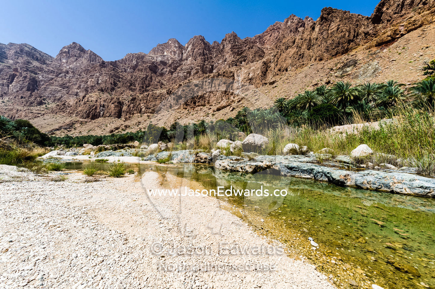 The clear waters of a river flowing through a desert gorge. Mibam, Wadi Tiwi, Sur Al Sharqiyah South Governorate, Sultanate of Oman.