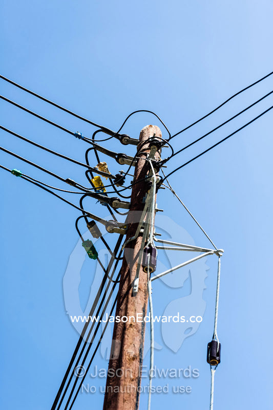 An electricity pole in a mountain village holds many connected wires. Mibam, Wadi Tiwi, Sur Al Sharqiyah South Governorate, Sultanate of Oman.