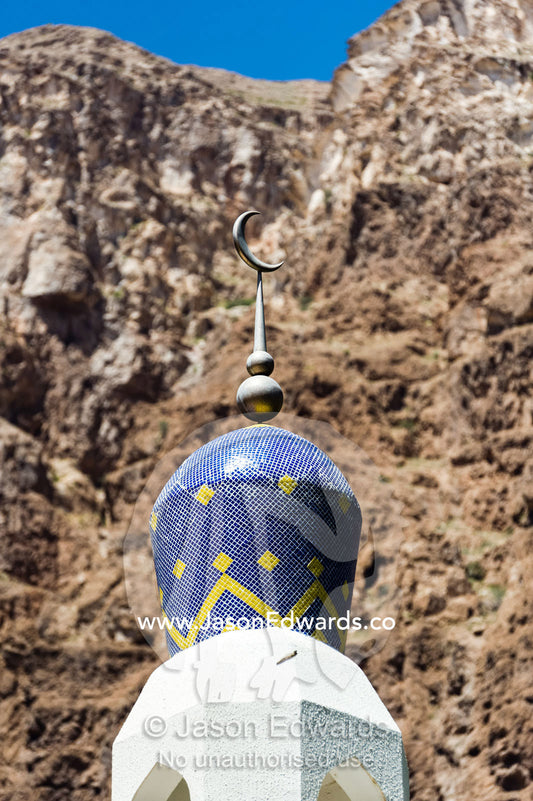 The colourful tiled dome of a minaret and mosque in a mountain village. Mibam, Wadi Tiwi, Sur Al Sharqiyah South Governorate, Sultanate of Oman.