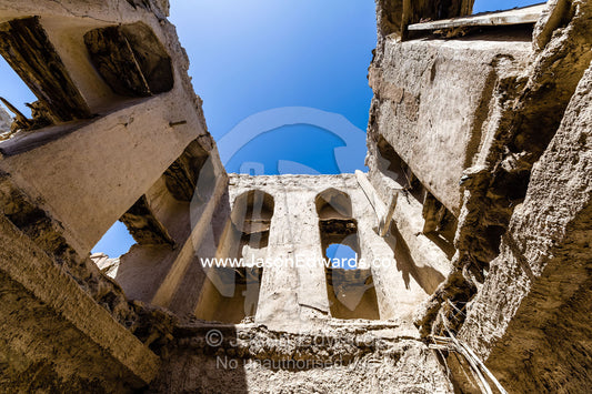 The sky is visible where the ceiling once was in a merchant home collapsing in a village in the desert. Ibra, Ash Sharqiyah Region, Sultanate of Oman.