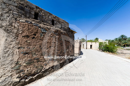 A narrow street winds it's way through an abandoned village in the desert. Ibra, Ash Sharqiyah Region, Sultanate of Oman.