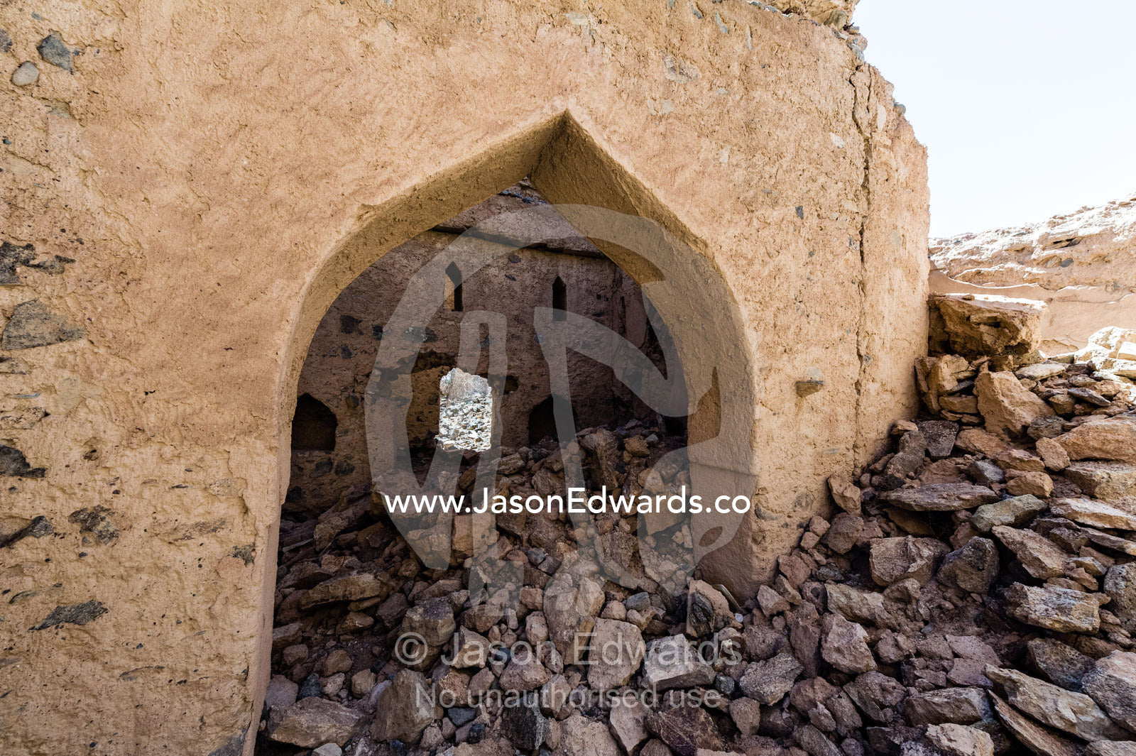 Ornate mudbrick archways and doorways above rubble collapsing in an abandoned village in the desert. Ibra, Ash Sharqiyah Region, Sultanate of Oman.