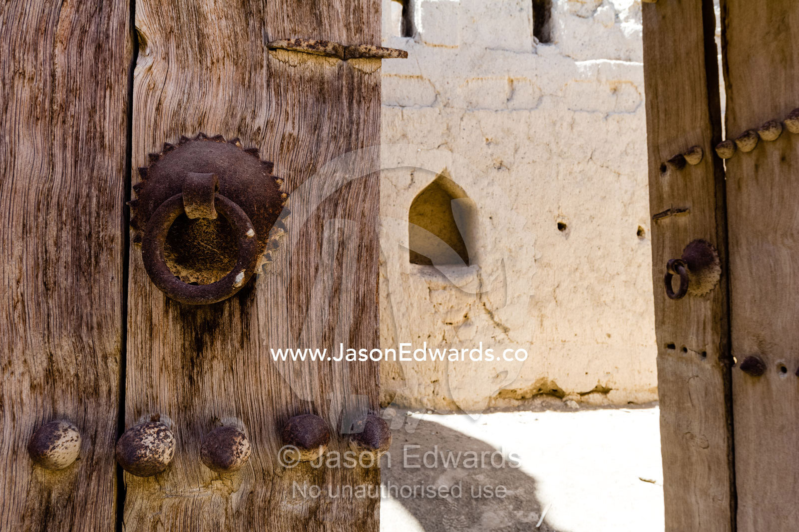 A rusting steel knocker on a timber door in an ancient desert village. Ibra, Ash Sharqiyah Region, Sultanate of Oman.