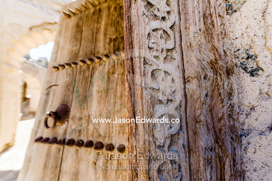 Ornate carving in the timber door frame of a home in an ancient desert village. Ibra, Ash Sharqiyah Region, Sultanate of Oman.