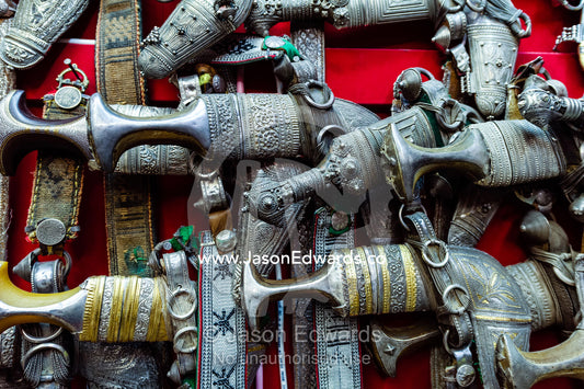 A wall displaying silver khanjar knives for sale in a souq. Mutrah Souq, Muscat, Sultanate of Oman.