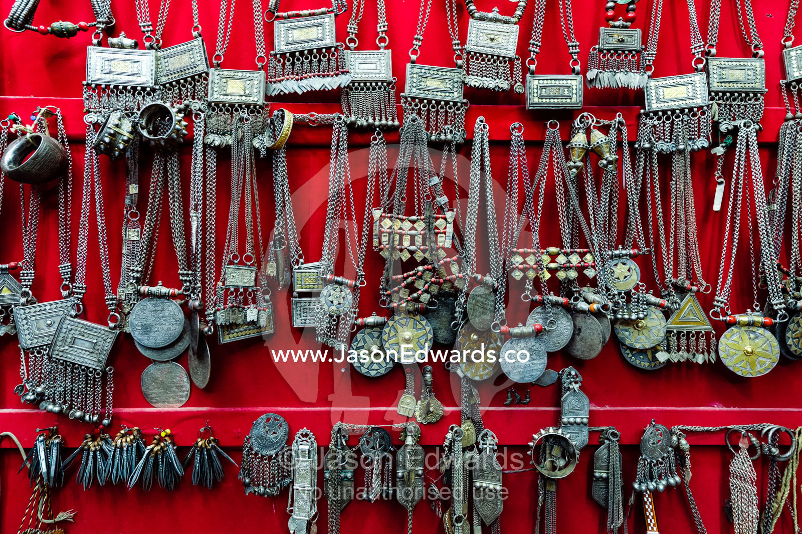 A wall displaying silver necklaces for sale in a souq. Mutrah Souq, Muscat, Sultanate of Oman.