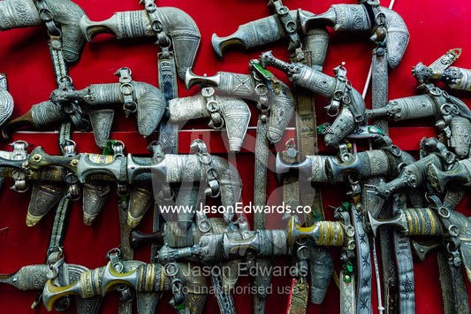 A wall displaying silver khanjar knives for sale in a souq. Mutrah Souq, Muscat, Sultanate of Oman.
