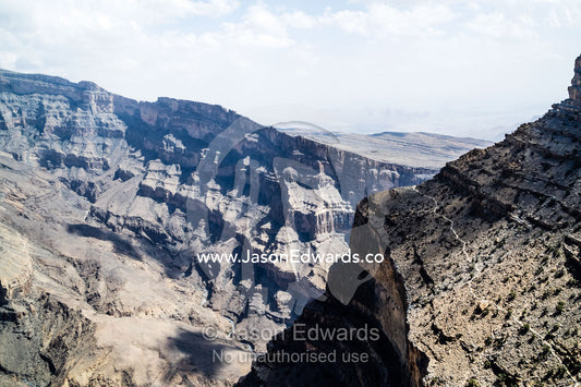Sheer cliff walls and terraces carved by erosion in a massive desert canyon. Wadi Ghul, Jebel Shams, Al Hajar Mountains, Sultanate of Oman.