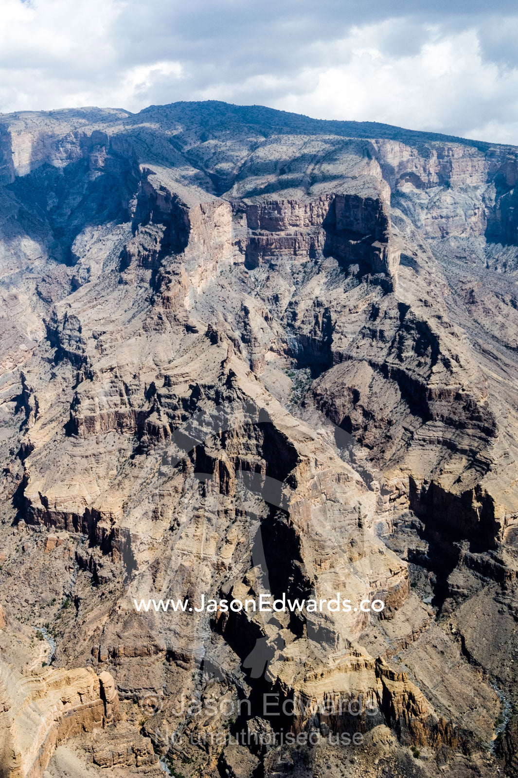 Sheer cliff walls and terraces carved by erosion in a massive desert canyon. Wadi Ghul, Jebel Shams, Al Hajar Mountains, Sultanate of Oman.