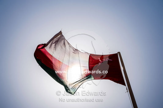 The flag of Oman flapping beneath the desert sun. Jabrin Fort, Ad Dakhiliyah Governorate, Sultanate of Oman.