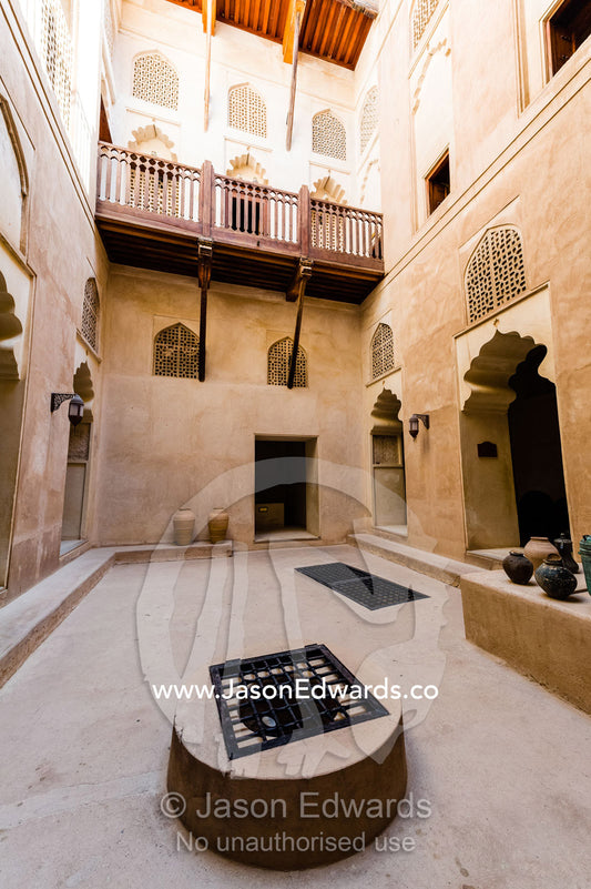 Timber balconies overlook latticed windows and a shaded well in an ancient fort courtyard. Jabrin Fort, Ad Dakhiliyah Governorate, Sultanate of Oman.