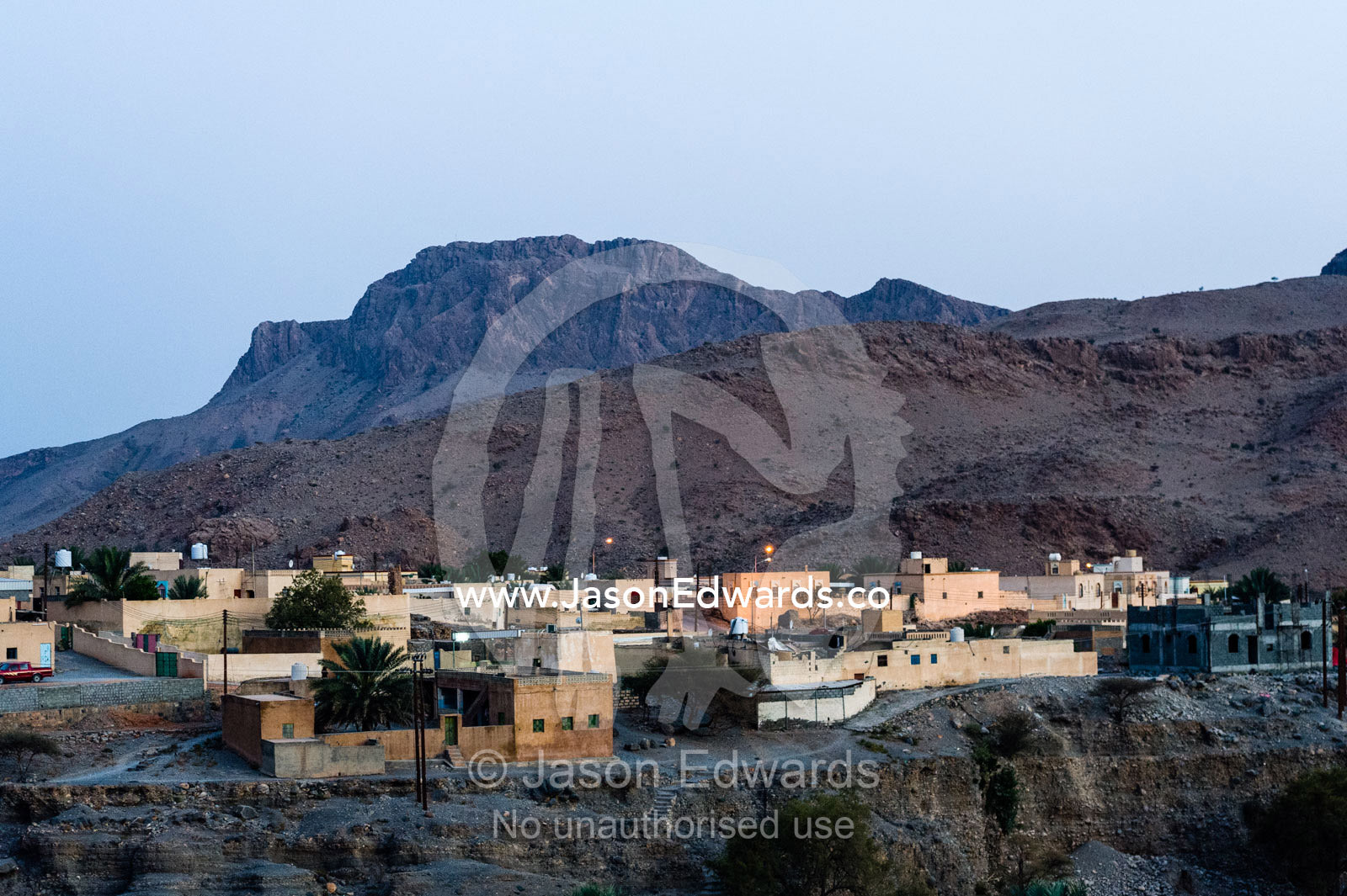 A village nestled on a cliff in a desert mountain valley. Wadi Nakhar, Al Hamra, Ad Dakhiliyah Region, Sultanate of Oman.