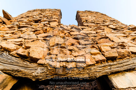 An ancient handmade stone building wall and timber door lintel in an abandoned desert village. Wadi Nakhar, Al Hamra, Ad Dakhiliyah Region, Sultanate of Oman.