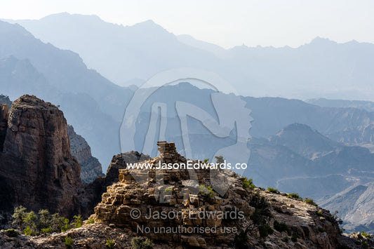 Arid jagged mountains overlook an eroded and inhospitable rocky desert valley. Hatt, Wadi Bani Awf, Snake Gorge, Western Hajar Mountains, Ad Dakhiliyah Region, Sultanate of Oman.