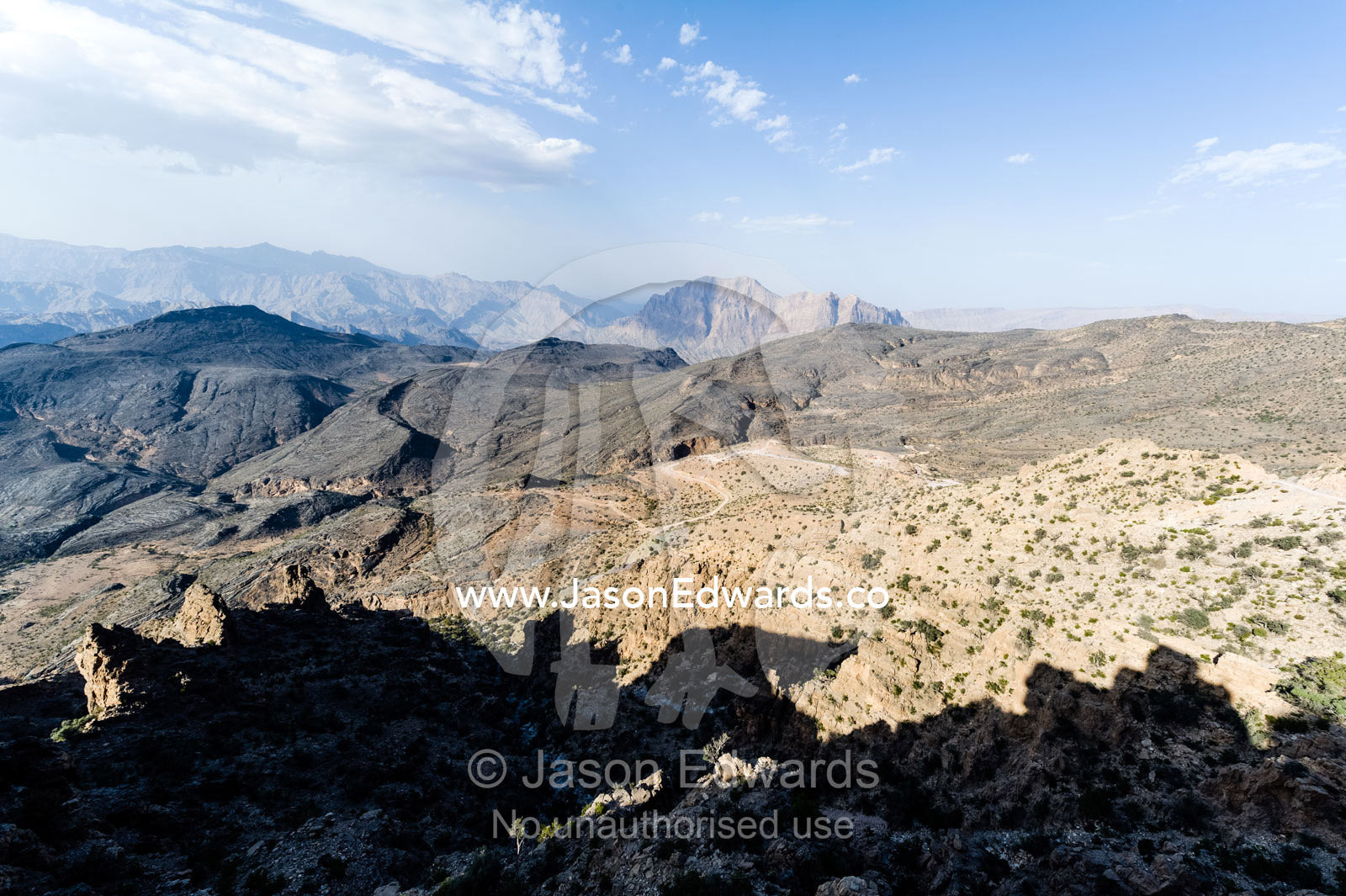 Arid jagged mountains overlook an eroded and inhospitable rocky desert valley. Hatt, Wadi Bani Awf, Snake Gorge, Western Hajar Mountains, Ad Dakhiliyah Region, Sultanate of Oman.