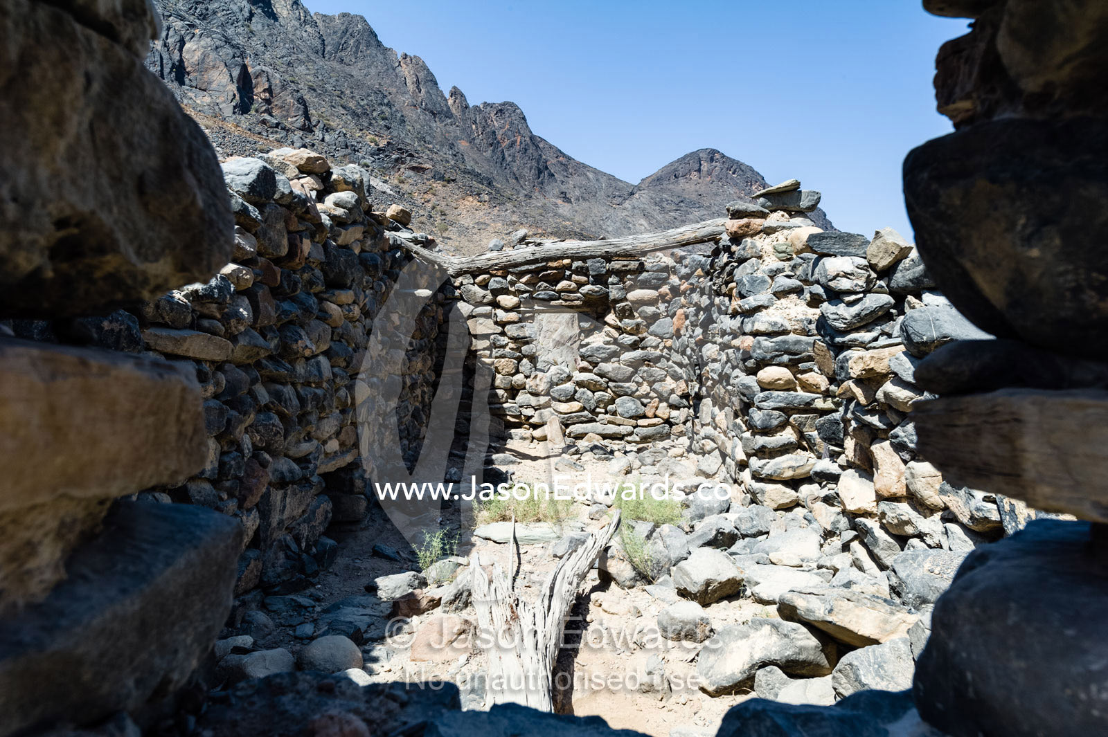 The ruins of a handmade stone house in an arid desert valley. Wadi Bani Awf, Snake Gorge, Western Hajar Mountains, Ad Dakhiliyah Region, Sultanate of Oman.