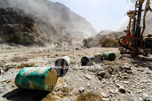 Oil drums and road construction machinery in a dusty desert gorge. Wadi Bani Awf, Snake Gorge, Western Hajar Mountains, Ad Dakhiliyah Region, Sultanate of Oman.