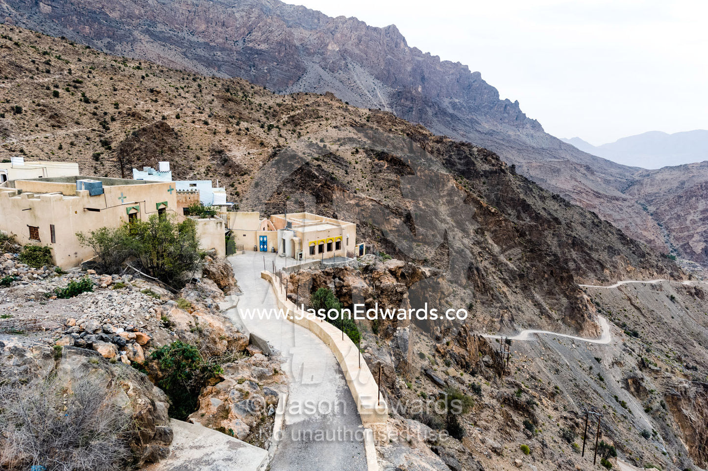 A village perched on a mountaintop overlooking an arid desert valley. Wakan Village, Wadi Mastal, Wilayt Nakhal, Al Batinah South Governorate, Sultanate of Oman.
