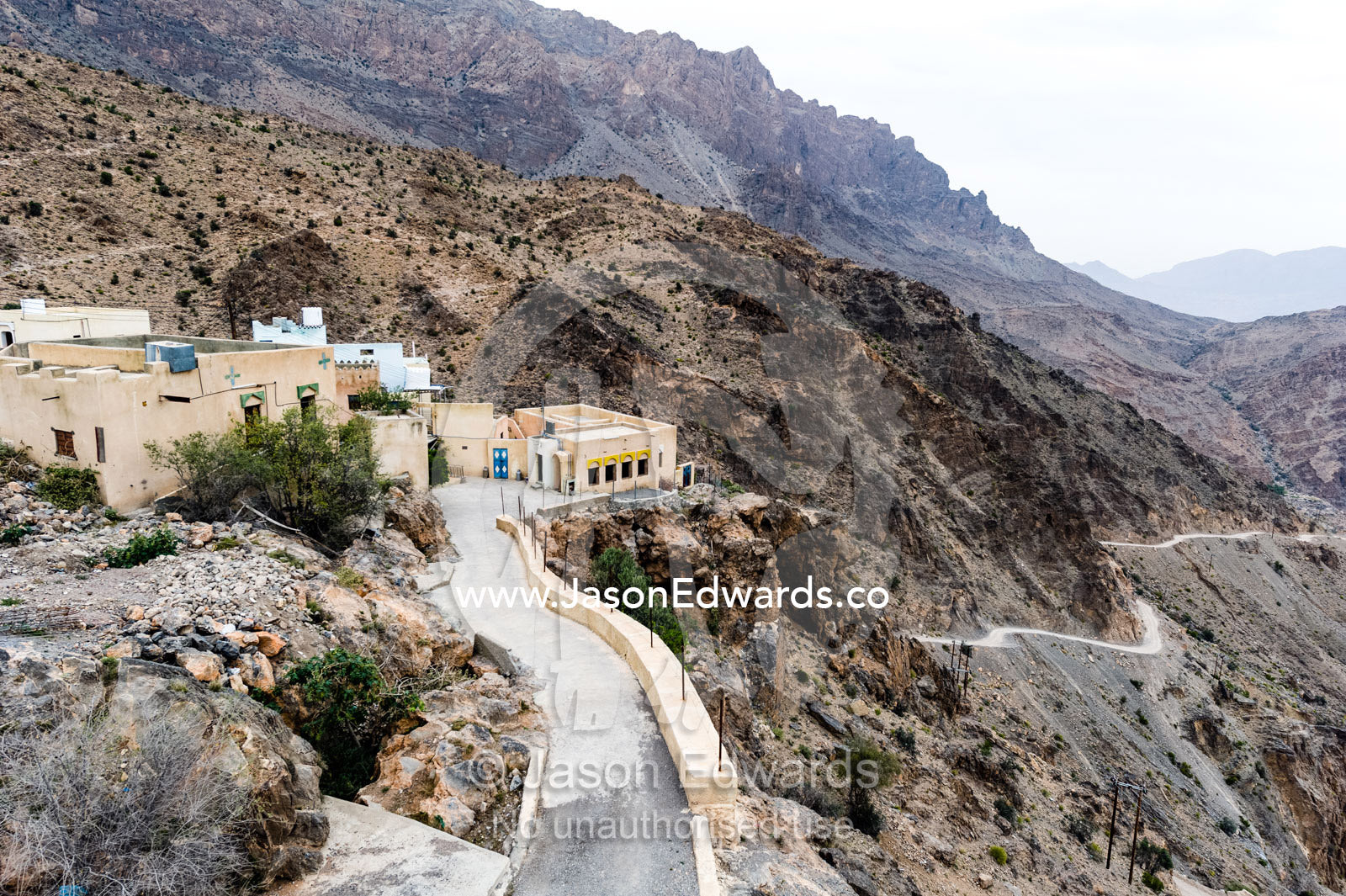A village perched on a mountaintop overlooking an arid desert valley. Wakan Village, Wadi Mastal, Wilayt Nakhal, Al Batinah South Governorate, Sultanate of Oman.