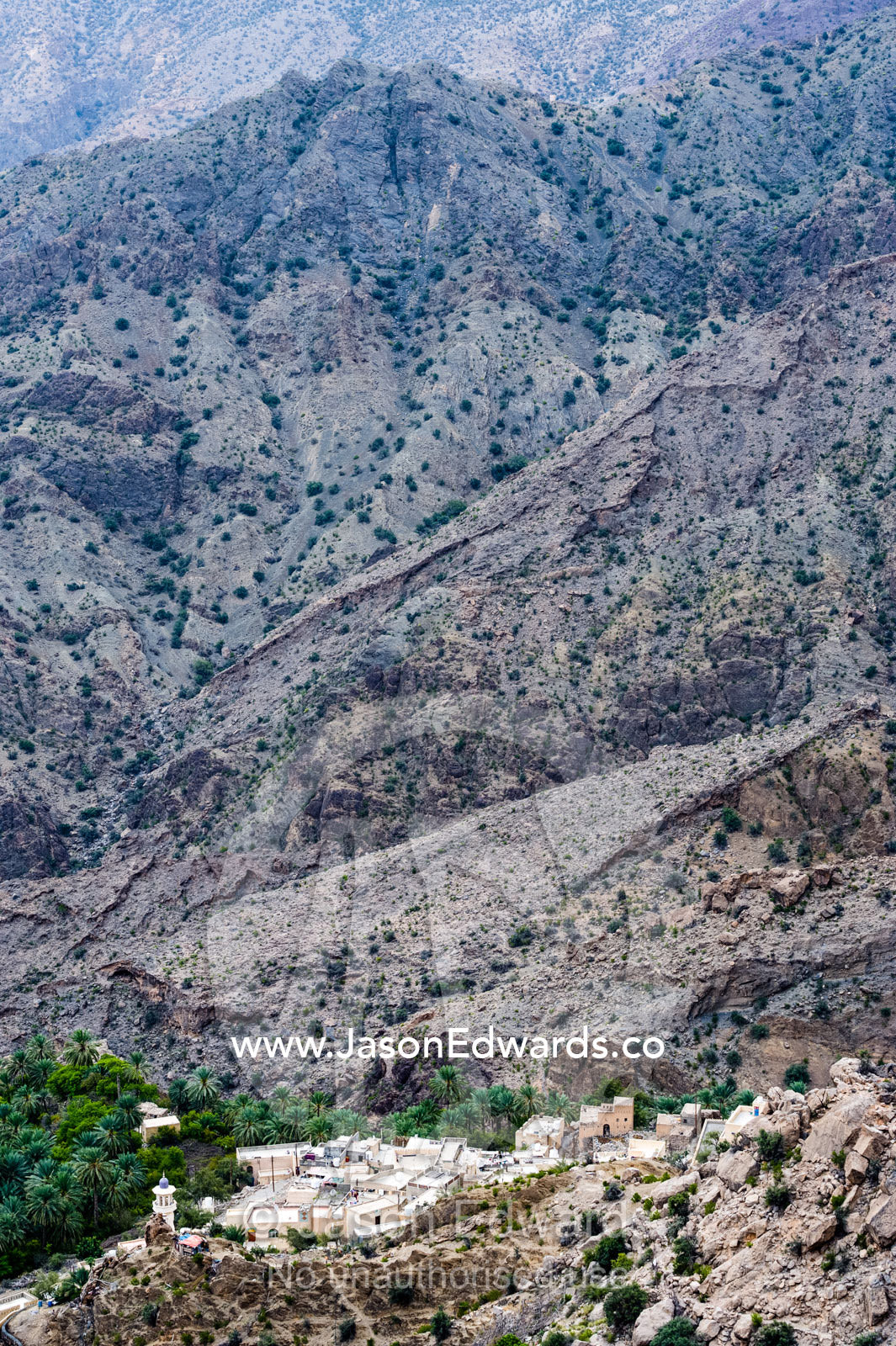 A village perched on a mountaintop overlooking an arid desert valley. Wakan Village, Wadi Mastal, Wilayt Nakhal, Al Batinah South Governorate, Sultanate of Oman.