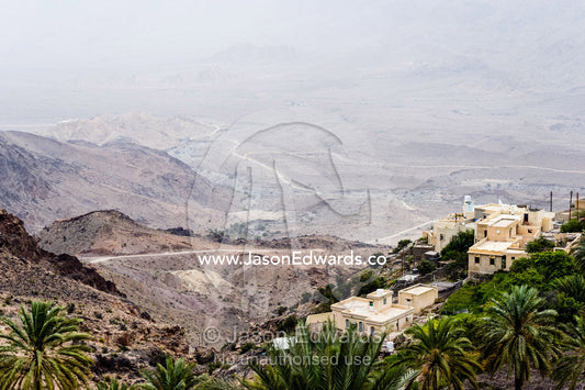 A village perched on a mountaintop overlooking an arid desert valley. Wakan Village, Wadi Mastal, Wilayt Nakhal, Al Batinah South Governorate, Sultanate of Oman.