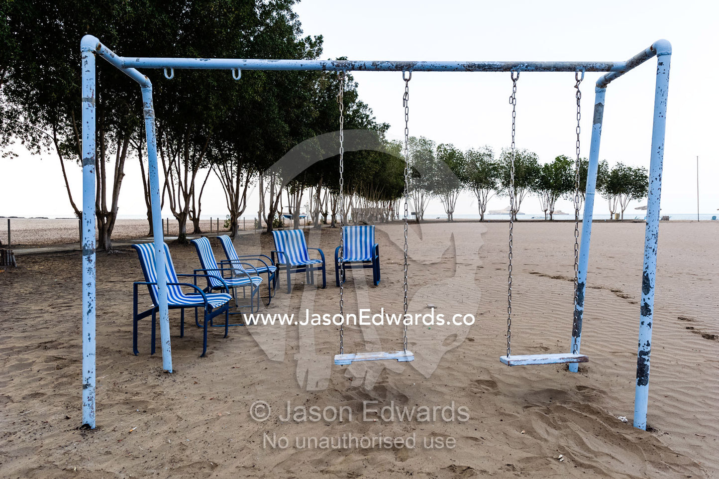 A weathered swing set and deck chairs on an empty beach on the Gulf of Oman. Daymaniyat Islands Nature Reserve, Wilayat AlSeeb, Barka, Sultanate of Oman.