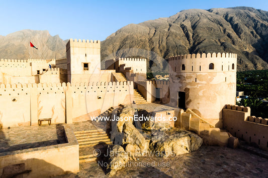 The ancient walls, parapets, battlements and watch tower of a fort on a desert mountaintop. Nakhal Fort, Wilayt Nakhal, Mount Nakhal, Al Batinah South Governorate, Sultanate of Oman.
