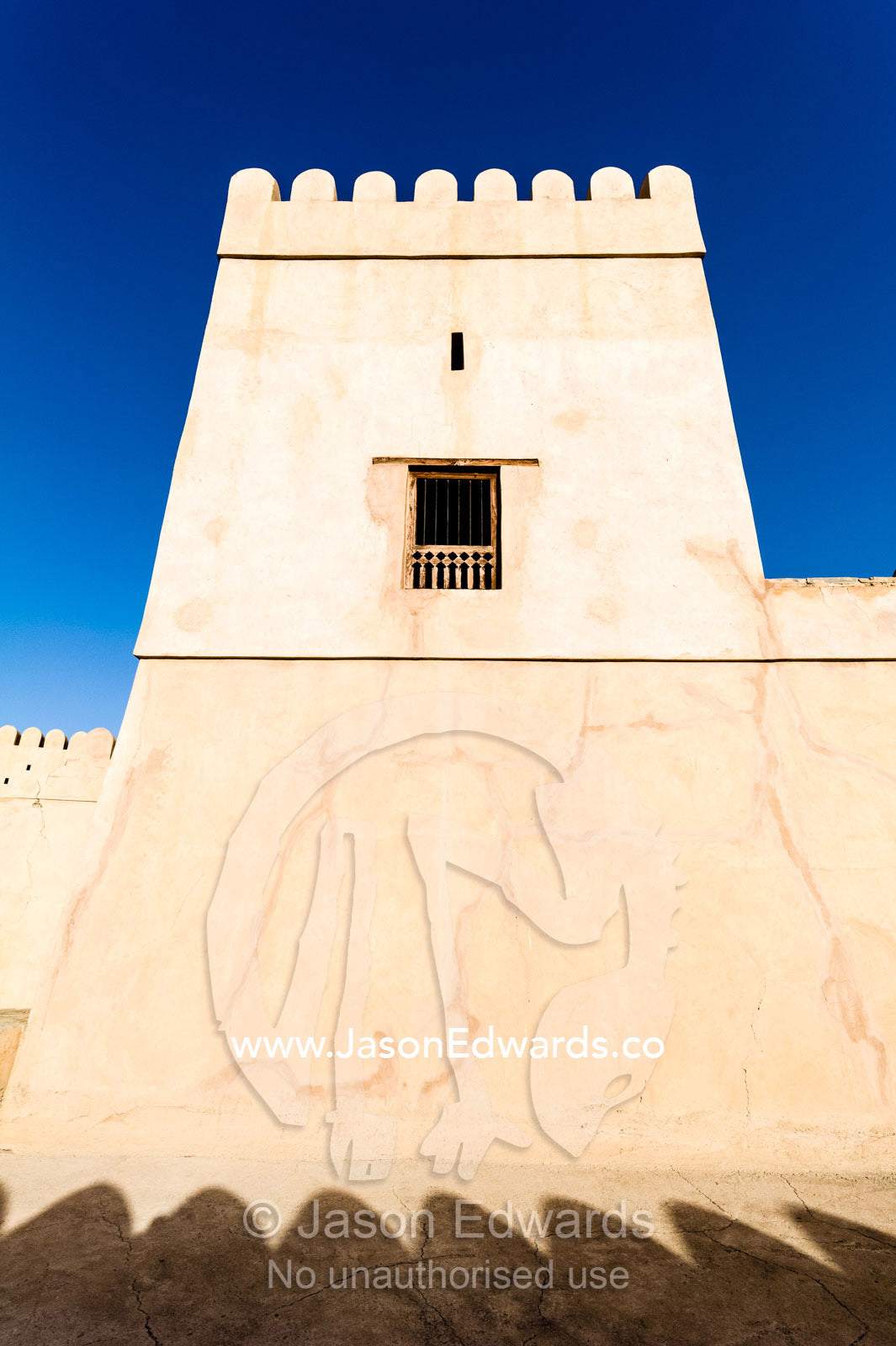 The ancient walls, parapets, battlements and watch tower of a fort on a desert mountaintop. Nakhal Fort, Wilayt Nakhal, Mount Nakhal, Al Batinah South Governorate, Oman.