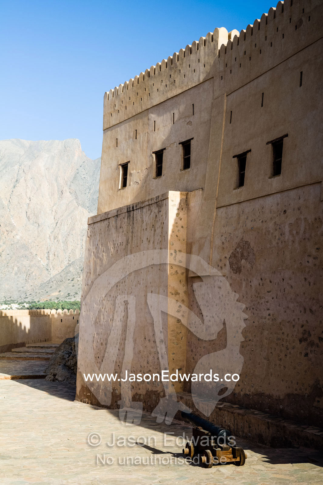 The ancient walls, parapets, battlements of a fort on a desert mountaintop. Nakhal Fort, Wilayt Nakhal, Mount Nakhal, Al Batinah South Governorate, Sultanate of Oman.
