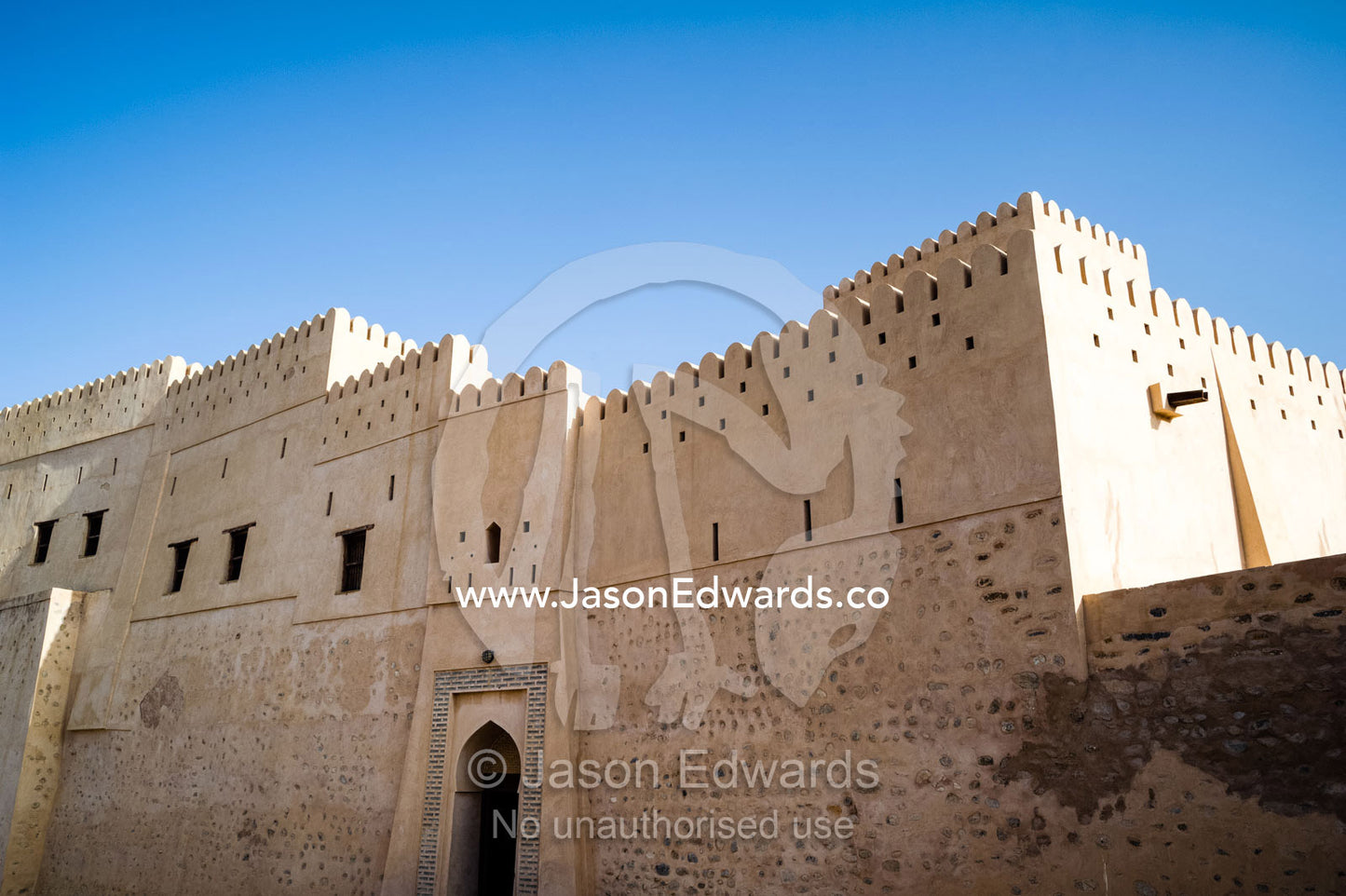 The ancient walls, parapets, battlements of a fort on a desert mountaintop. Nakhal Fort, Wilayt Nakhal, Mount Nakhal, Al Batinah South Governorate, Sultanate of Oman.