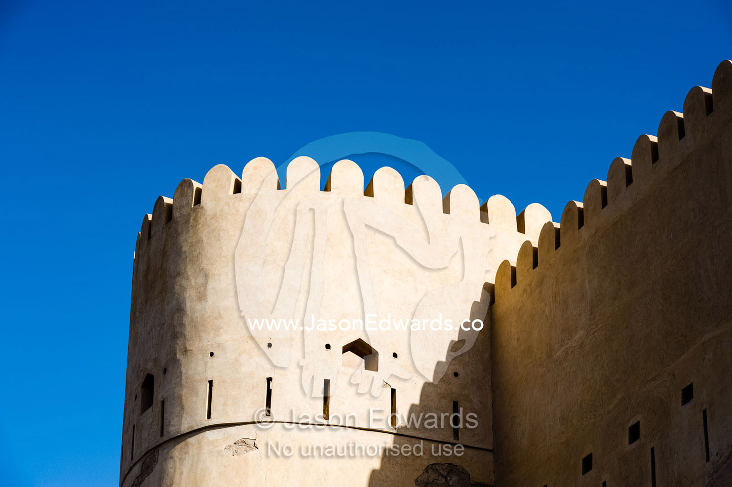 The ancient walls, parapets and battlements and watch tower of a fort on a desert mountaintop. Nakhal Fort, Wilayt Nakhal, Mount Nakhal, Al Batinah South Governorate, Sultanate of Oman.