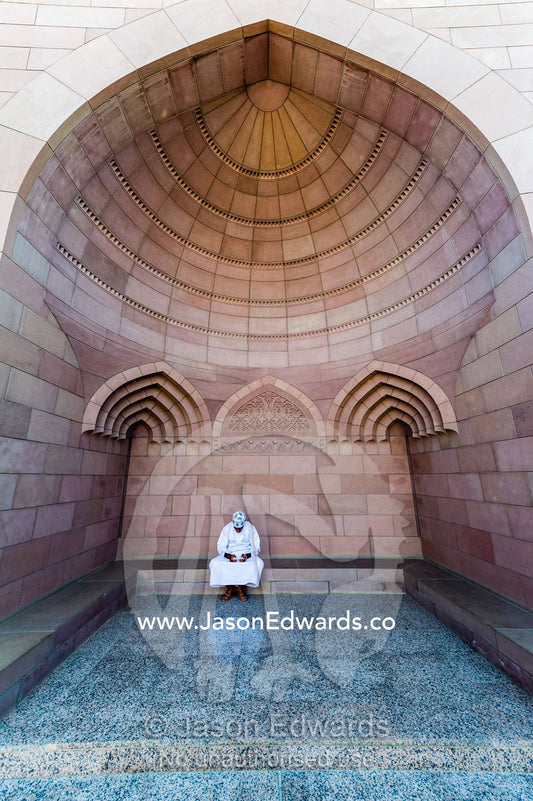 A Muslim man in a dishdasha and kuma texting on his mobile phone at the Grand Mosque. Sultan Qaboos Grand Mosque, Muscat, Sultanate of Oman.