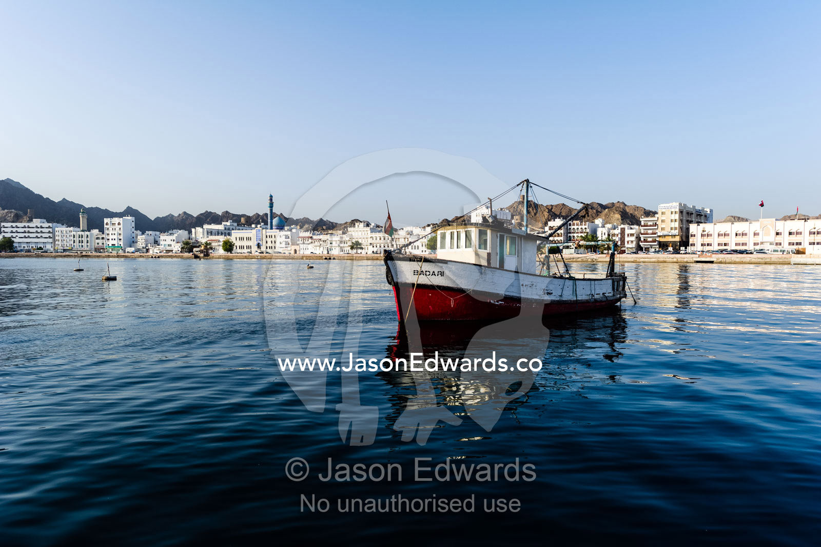 An old fishing boat settled in the tranquil waters of a bay. Muscat, Gulf of Oman, Sultanate of Oman.