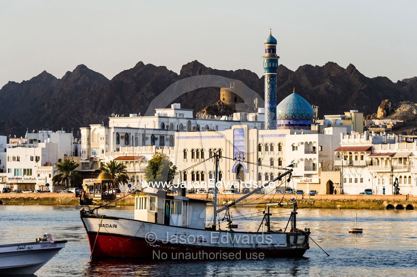 An old fishing boat settled in the tranquil waters of a bay. Muscat, Gulf of Oman, Sultanate of Oman.