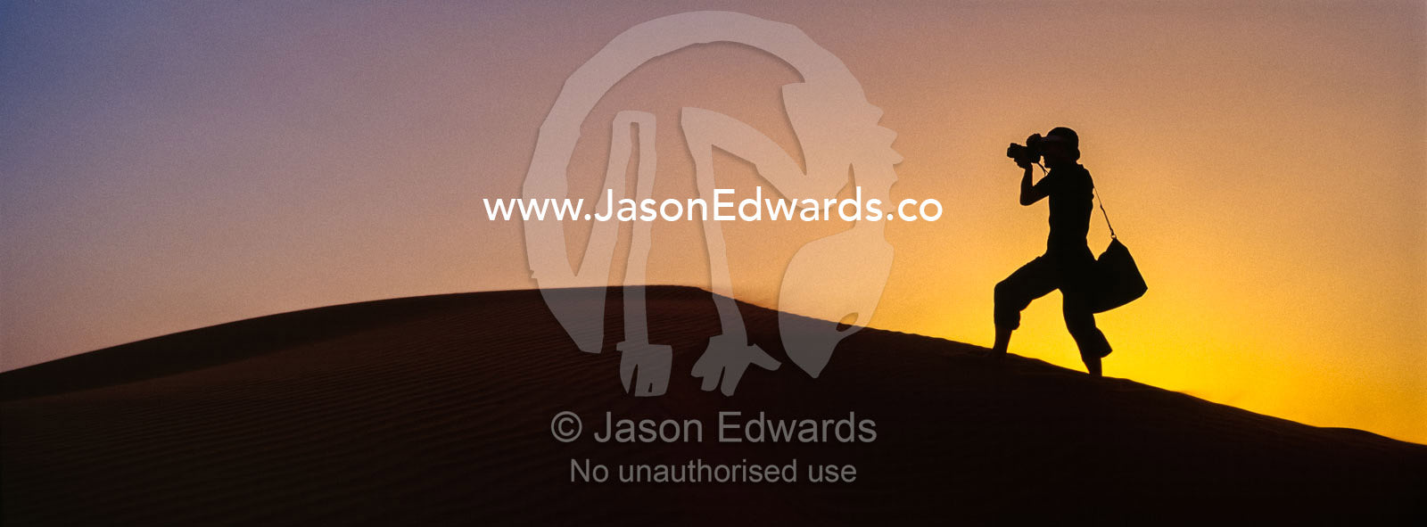 The silhouette of a photographer taking photos on a sand dune at sunset. Wahiba Sands, Ramlat al-Wahiba, Sharqiya Sands, Sultanate of Oman.