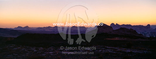 Pastel sunset afterglow on the horizon above jagged deserts mountains. Al Hajar Mountains, Al Hamra, Ad Dakhiliyah Region, Sultanate of Oman.