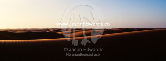 Sunset shines on sand dunes in the desert. Wahiba Sands, Ramlat al-Wahiba, Sharqiya Sands, Sultanate of Oman.