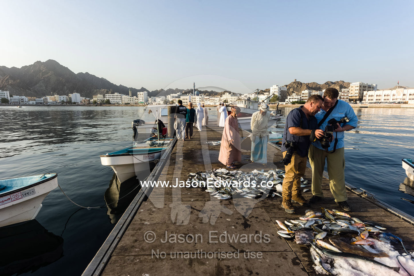 A photographer instructing a scholarship recipient about photography at a fish market. Mutrah Fish Market, Muscat, Gulf of Oman, Sultanate of Oman.
