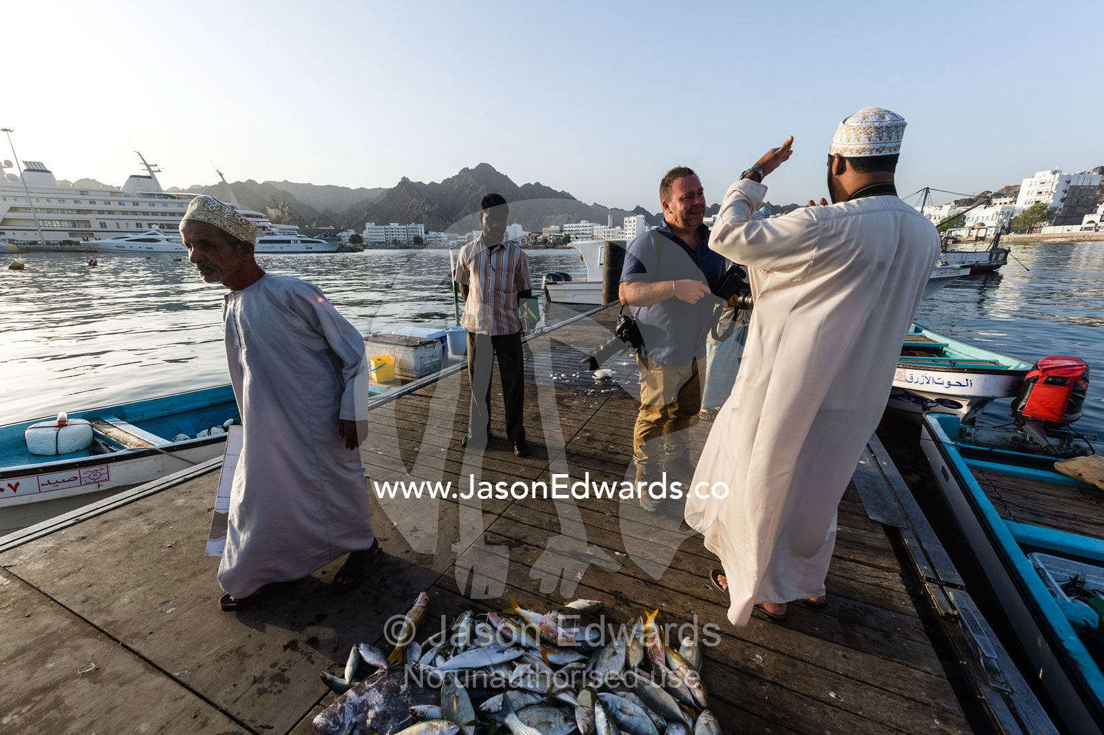 A photographer discussing locations with his fixer at a fish market. Mutrah Fish Market, Muscat, Gulf of Oman, Sultanate of Oman.