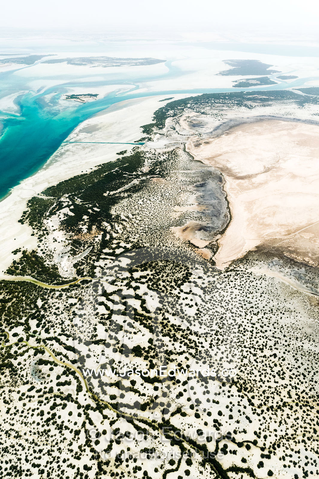 Turquoise tidal flats and coastal sea channels surrounded by arid desert sands. Emirate of Abu Dhabi, Abu Dhabi, Persian Gulf, United Arab Emirates.