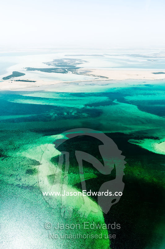 Turquoise tidal flats and coastal sea channels surrounded by arid desert sands. Emirate of Abu Dhabi, Abu Dhabi, Persian Gulf, United Arab Emirates.