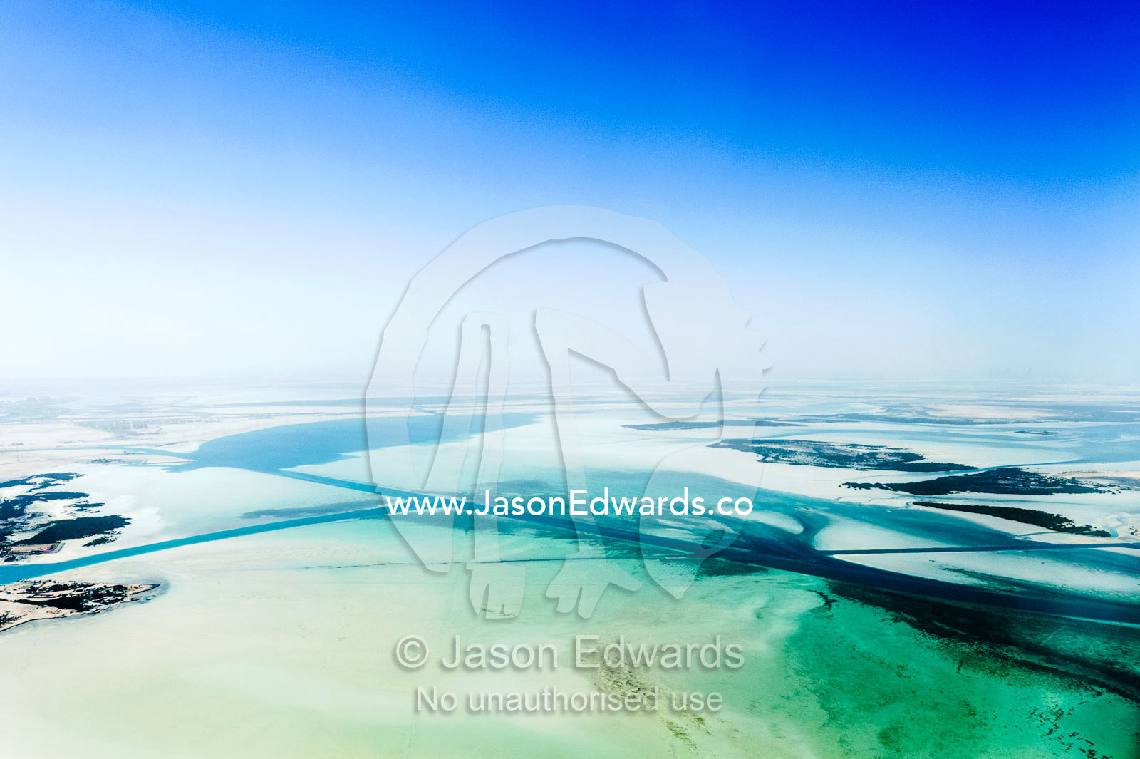 Turquoise tidal flats and coastal sea channels surrounded by arid desert sands. Emirate of Abu Dhabi, Abu Dhabi, Persian Gulf, United Arab Emirates.