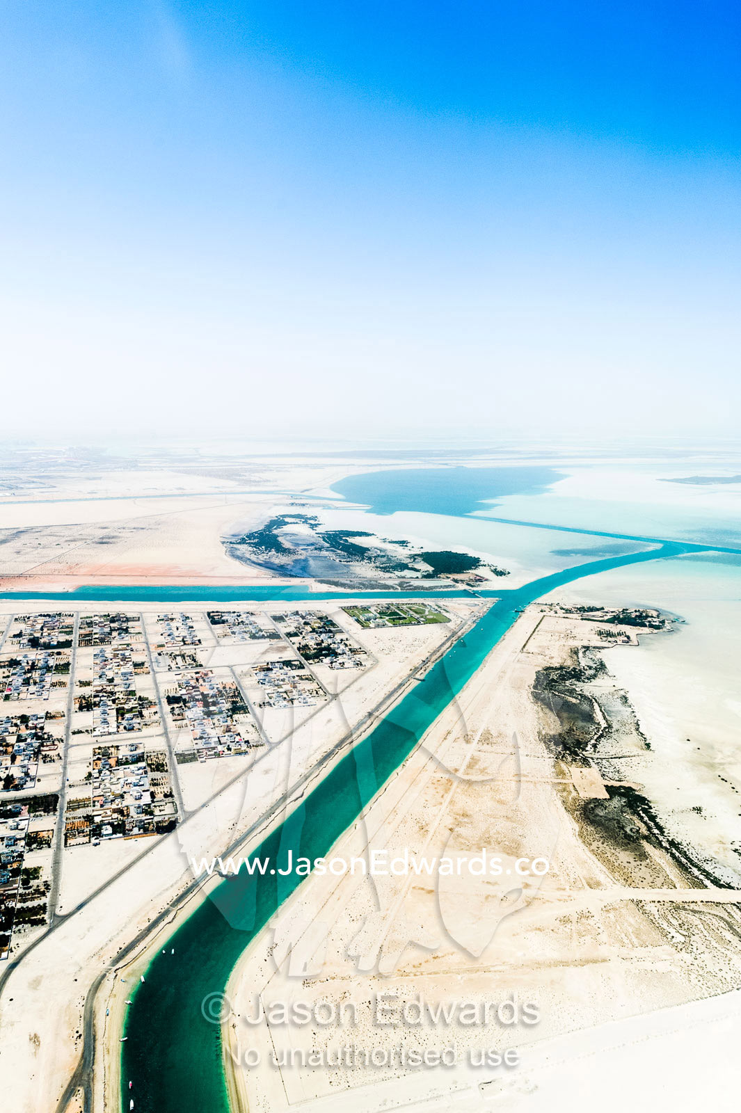 Manmade turquoise channels lead from the ocean to suburban residential estates and homes. Emirate of Abu Dhabi, Abu Dhabi, Persian Gulf, United Arab Emirates.