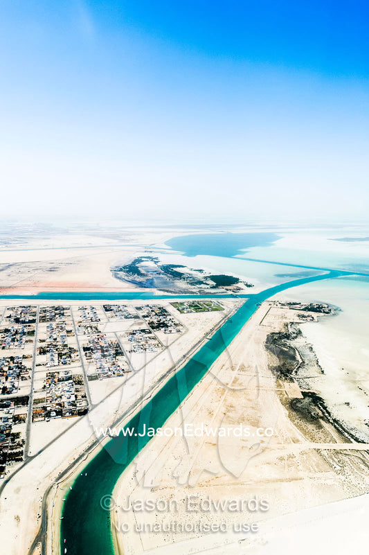 Manmade turquoise channels lead from the ocean to suburban residential estates and homes. Emirate of Abu Dhabi, Abu Dhabi, Persian Gulf, United Arab Emirates.