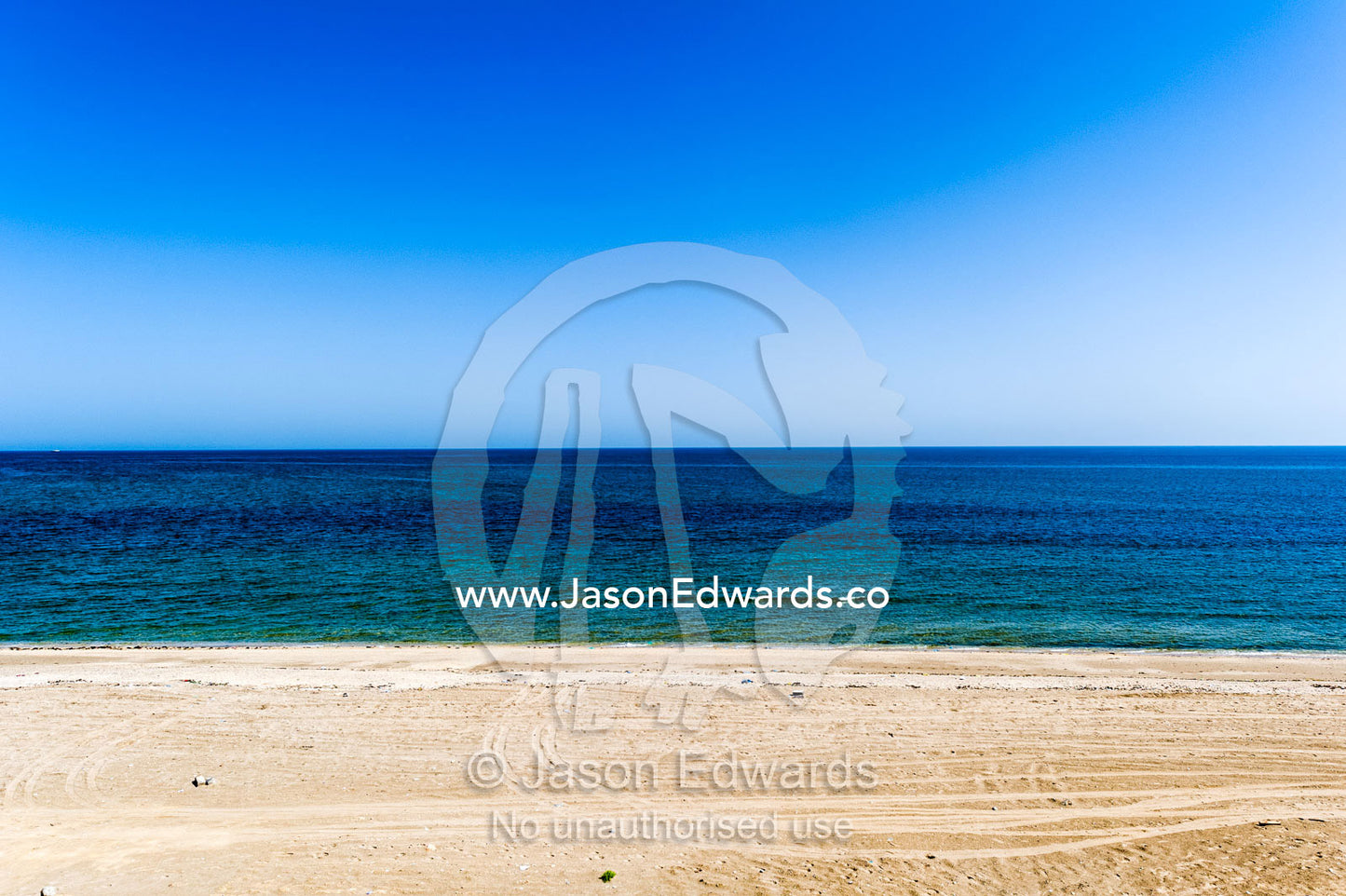 An empty, flat sandy beach overlooks the blue seas of the Gulf of Oman. Sur Beach Hotel, Sur, Ash Sharqiyah Region, Gulf of Oman, Sultanate of Oman.