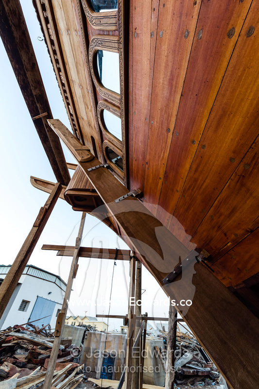 The handmade construction of an ancient timber dhow in a shipyard and the fitting of the rudder. Sur, Ash Sharqiyah Region, Gulf of Oman, Sultanate of Oman.