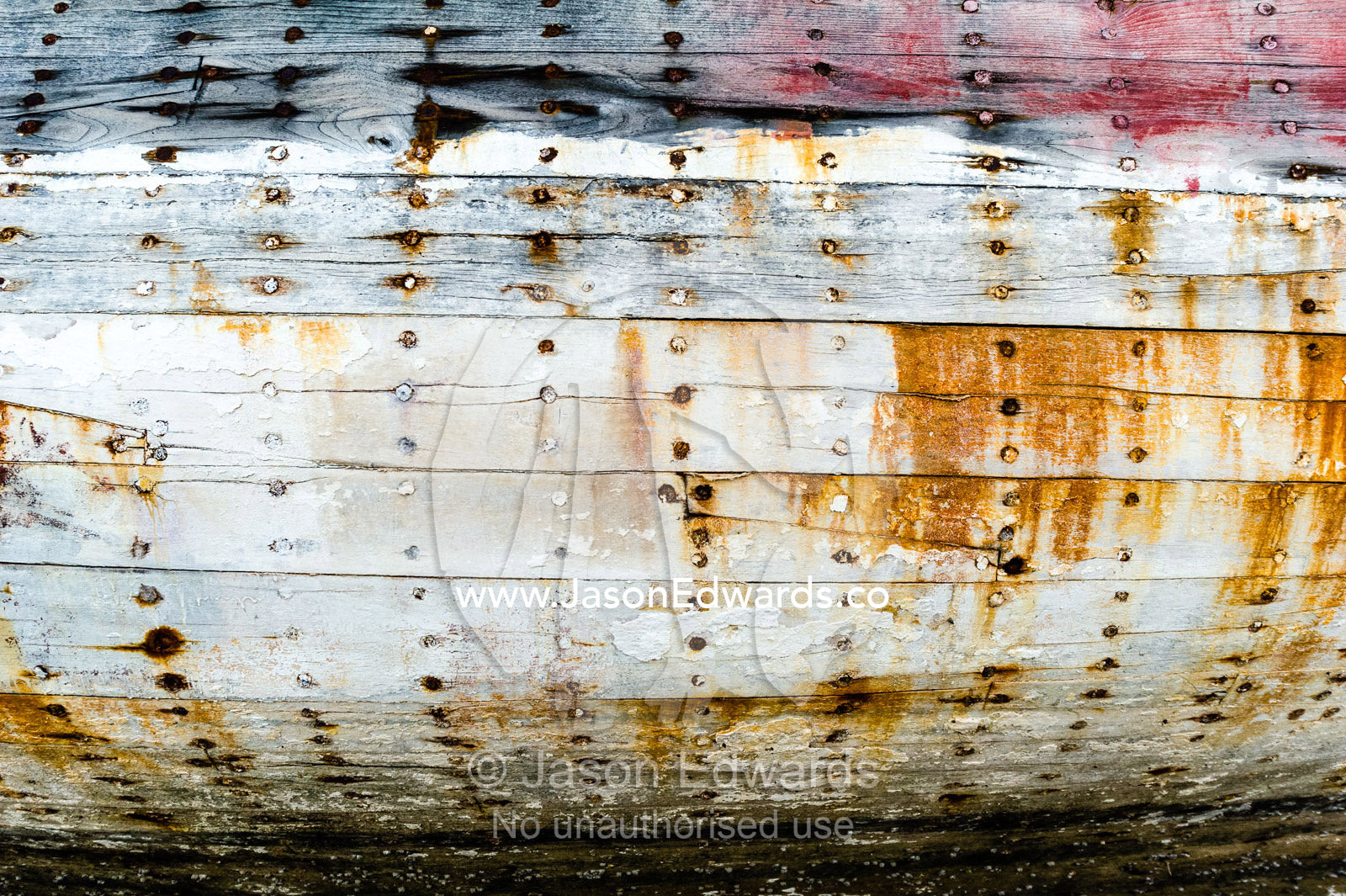 Rusting nails and faded and weathered planks on the hull of a dhow on the beach at low tide. Sur, Ash Sharqiyah Region, Gulf of Oman, Sultanate of Oman.