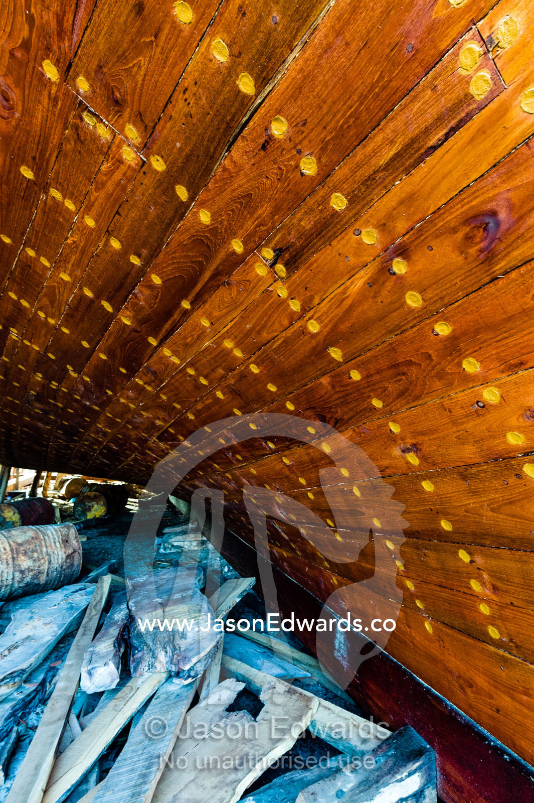 Nail holes filled with putty and freshly oiled timber hull planks on a dhow under construction. Sur, Ash Sharqiyah Region, Gulf of Oman, Sultanate of Oman.