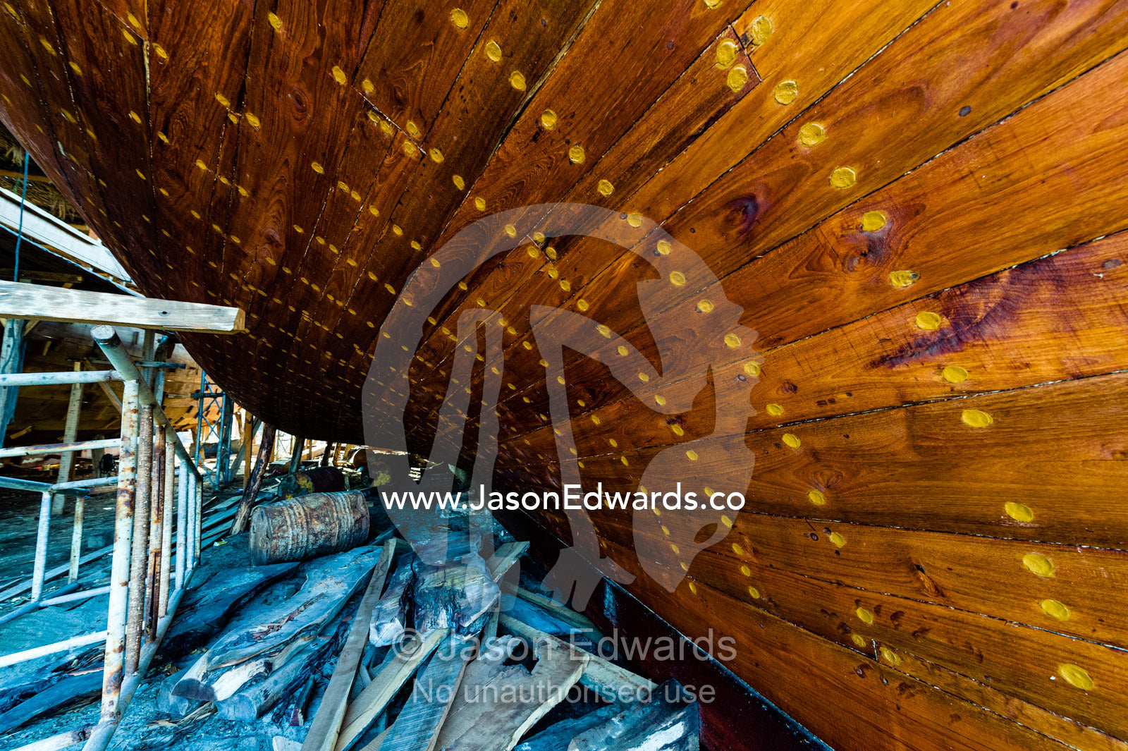 Nail holes filled with putty and freshly oiled timber hull planks on a dhow under construction. Sur, Ash Sharqiyah Region, Gulf of Oman, Sultanate of Oman.