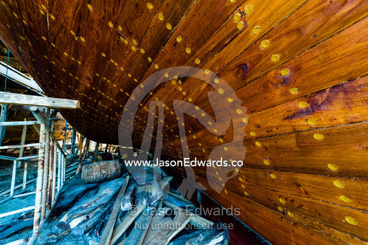 Nail holes filled with putty and freshly oiled timber hull planks on a dhow under construction. Sur, Ash Sharqiyah Region, Gulf of Oman, Sultanate of Oman.